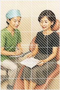 診療チェア上でインプラント治療の説明を受ける患者と、資料を用いて説明する歯科スタッフの写真